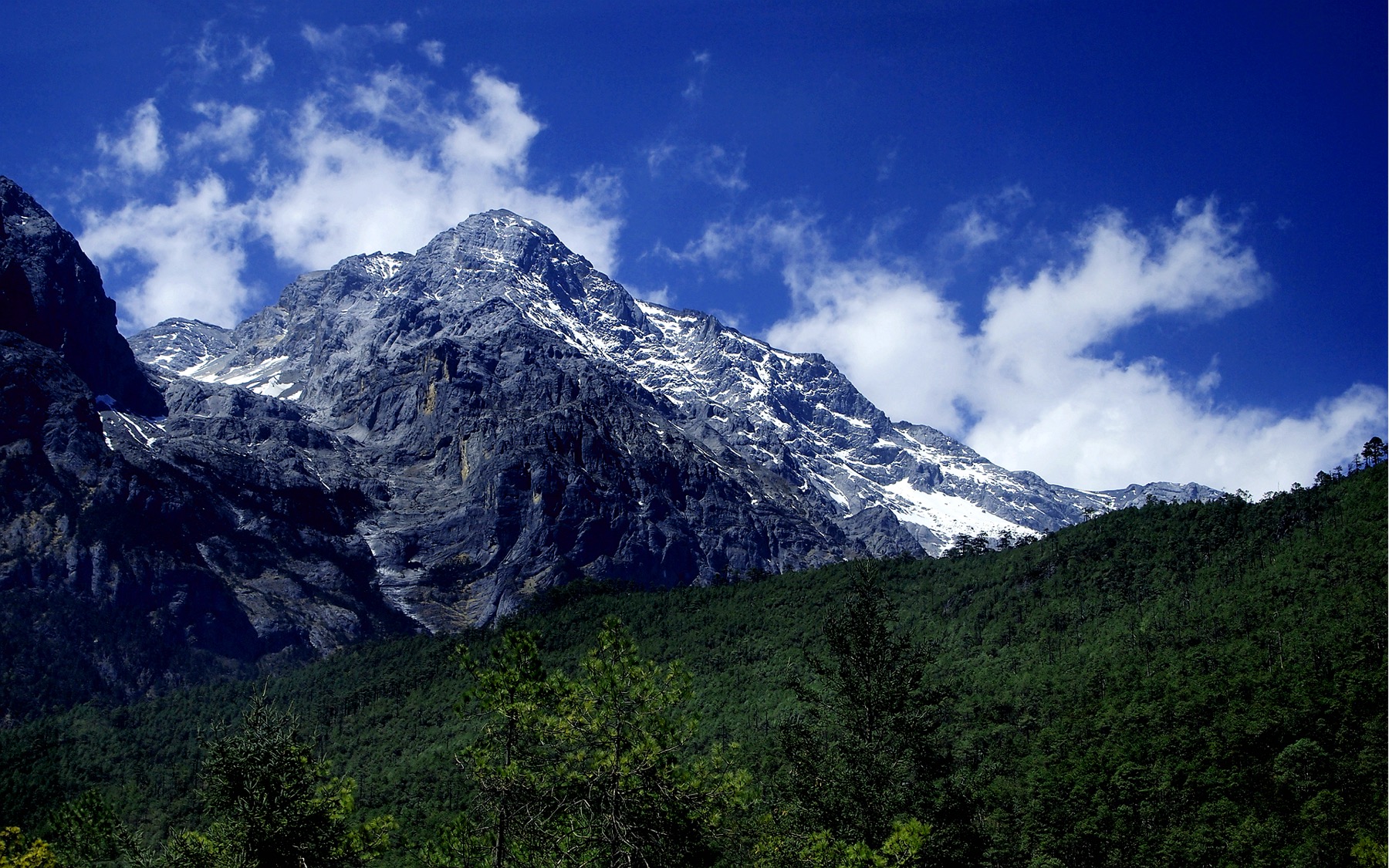 Snowy Jade Dragon Snow Mountain rising above forest near Blue Moon Valley in Lijiang.