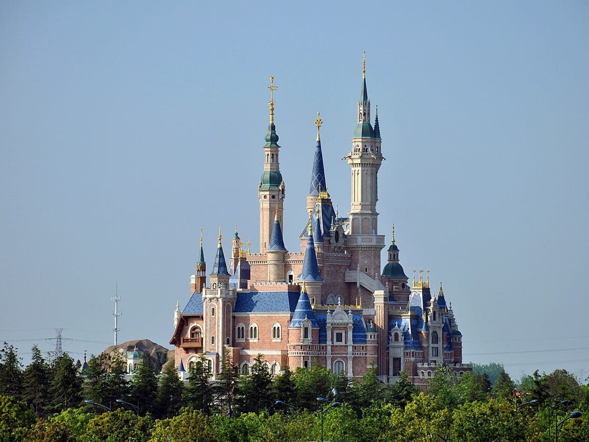 Shanghai Disney castle lit in bright colors at night.