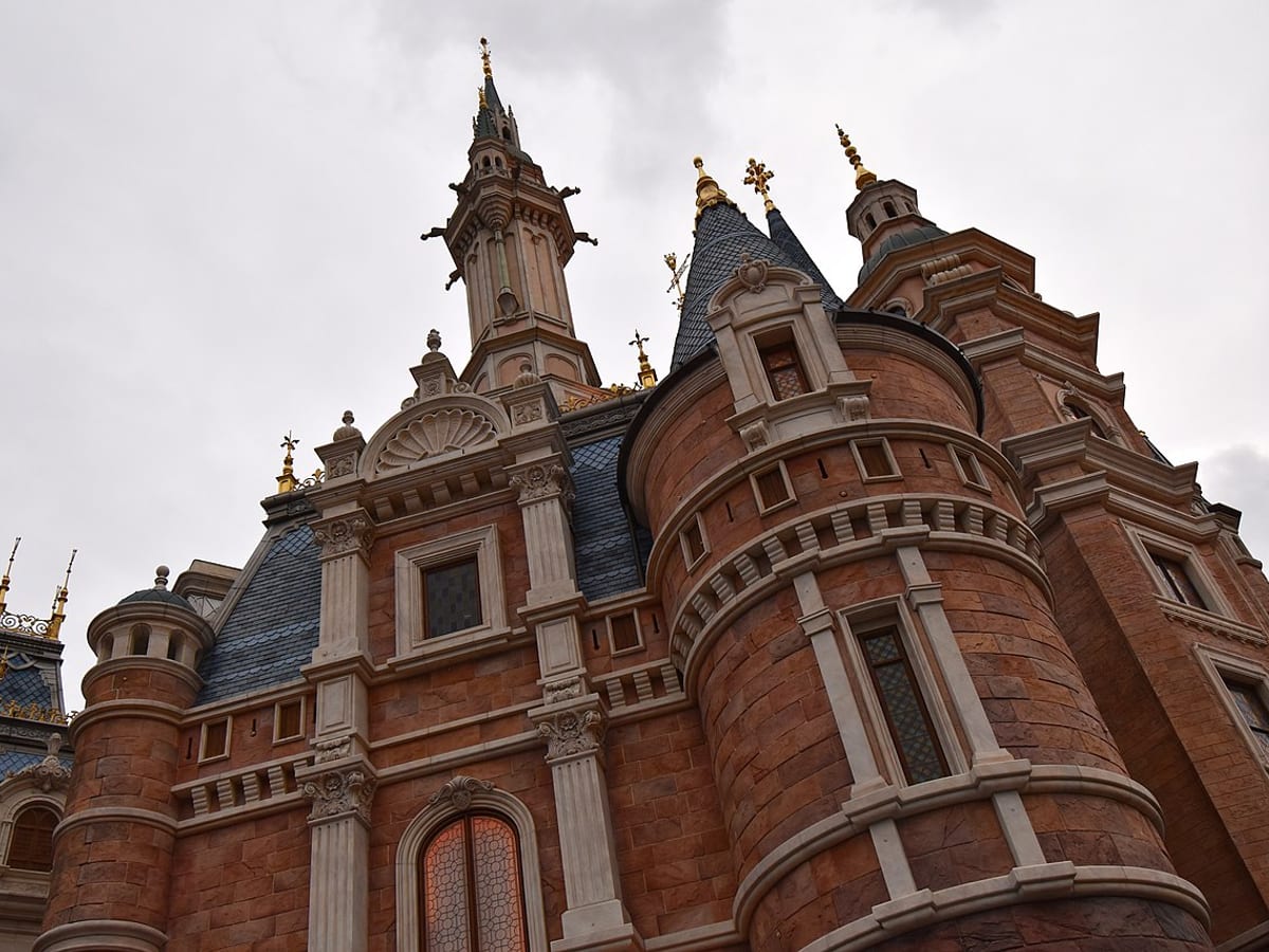Shanghai Disney castle show with warm golden lighting.