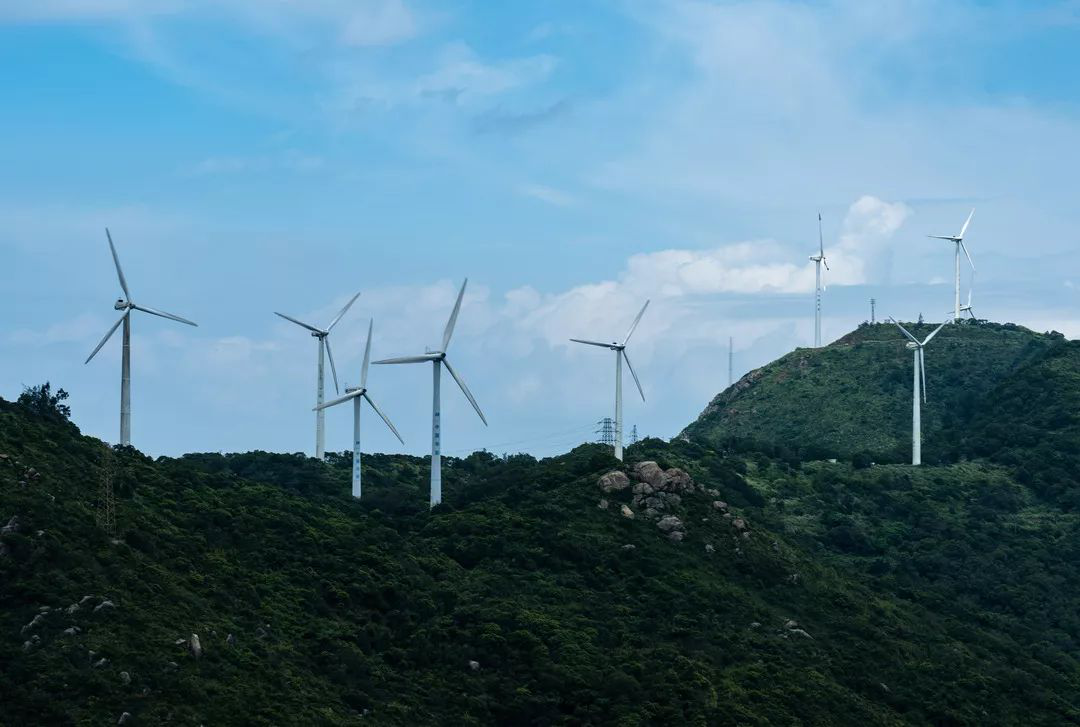 Wind turbines on the green hills of Nan'ao Island above the sea.