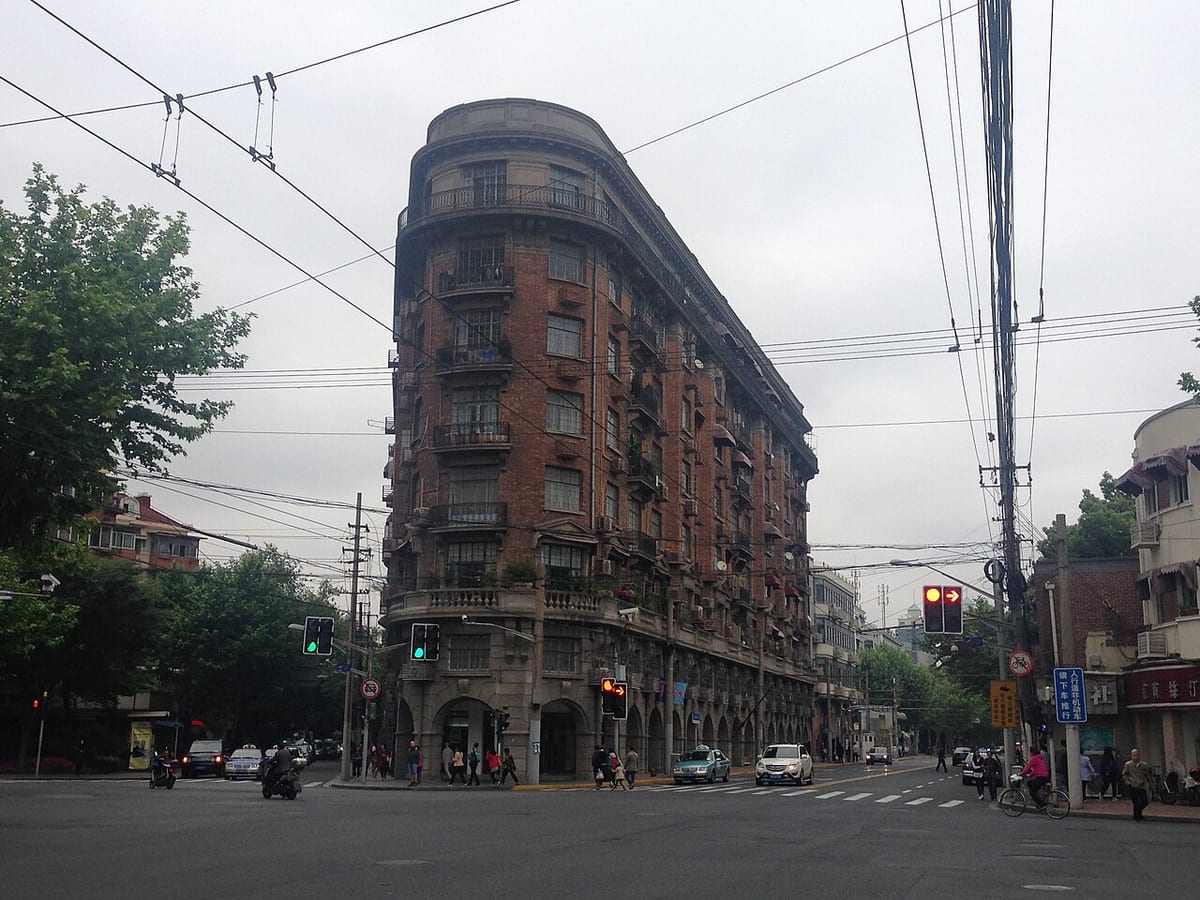 Wukang Mansion facade in Shanghai framed by tree branches.